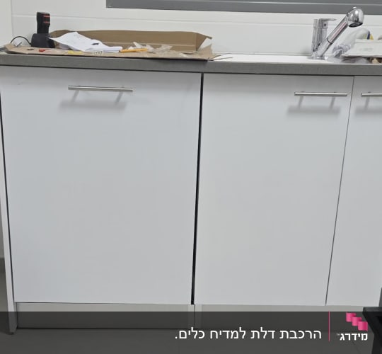 ארונות מטבח עם כלים וחומרים על השיש
